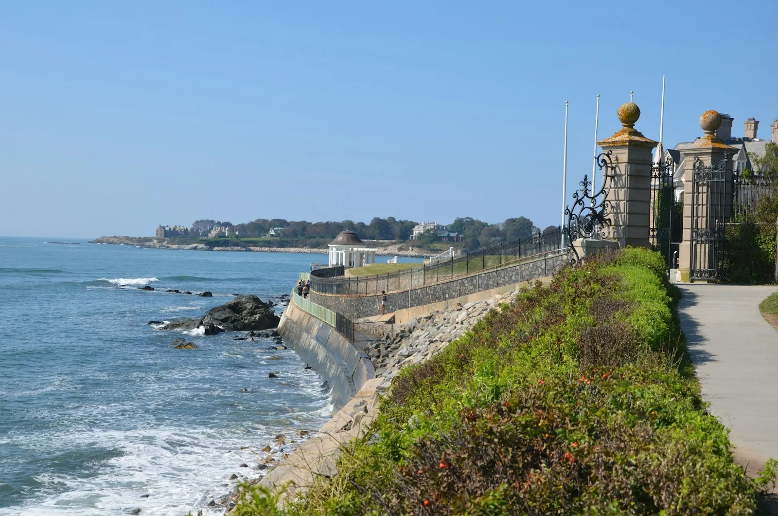 The Cliff Walk in Newport, Rhode Island, a paved path between a seawall above the ocean and the iron gates of a Gilded Age mansion