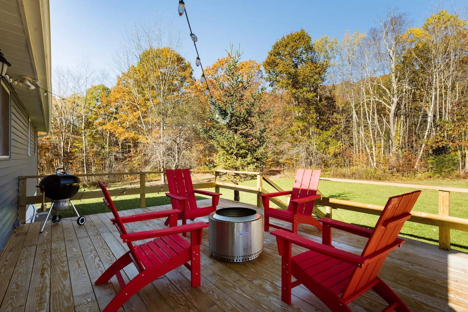 Red Adirondack chairs around a Solo Stove fire pit on the deck at Clove Creek Cabin in Hunter, NY