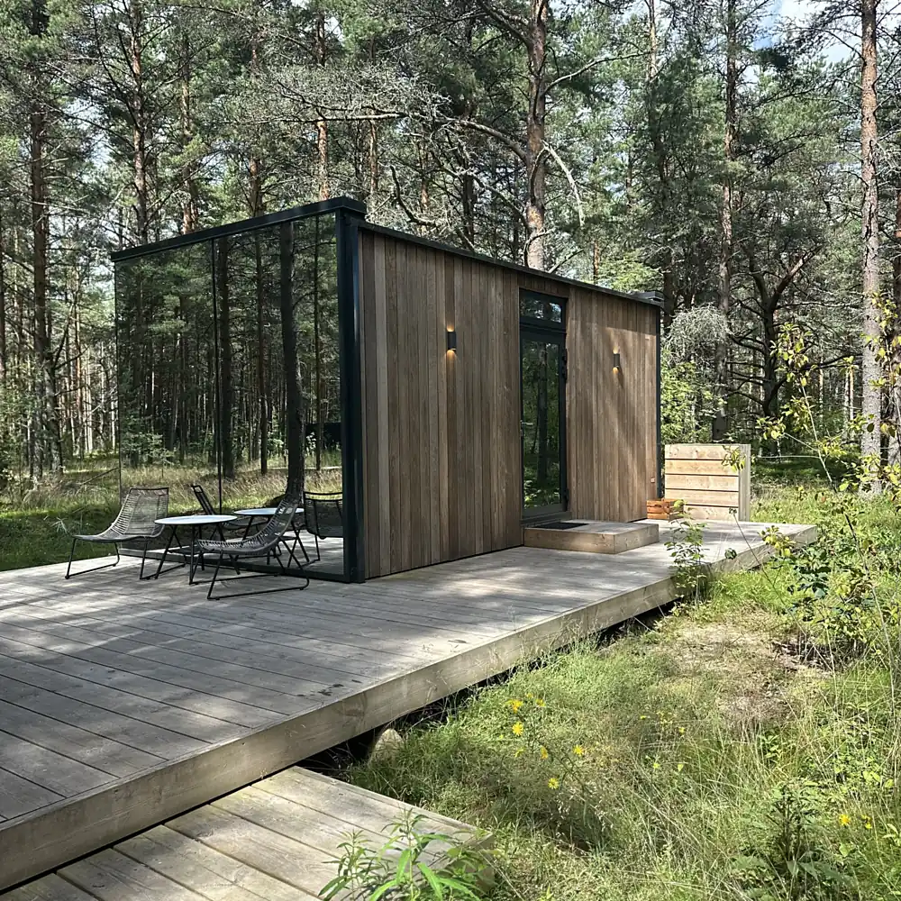 Modern glass-and-wood cabin on a wide deck in a pine forest
